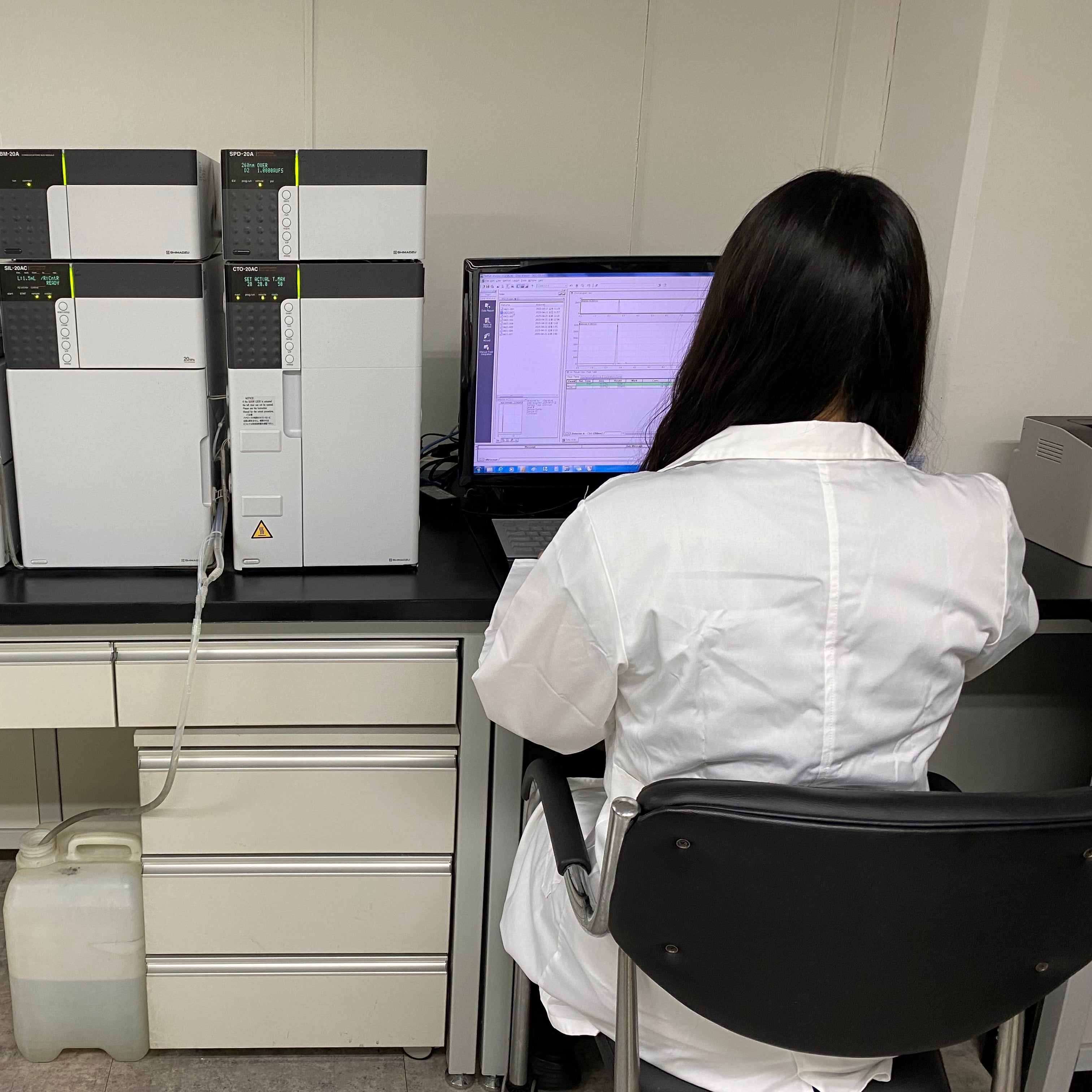 Person in a lab coat working at a computer in a laboratory setting